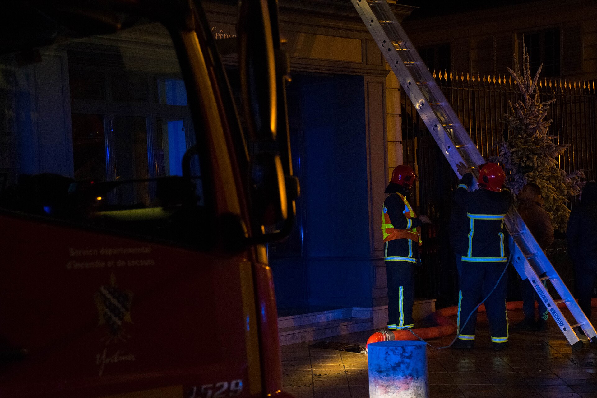 Sapeurs-pompiers dressant une échelle contre une façade, de nuit